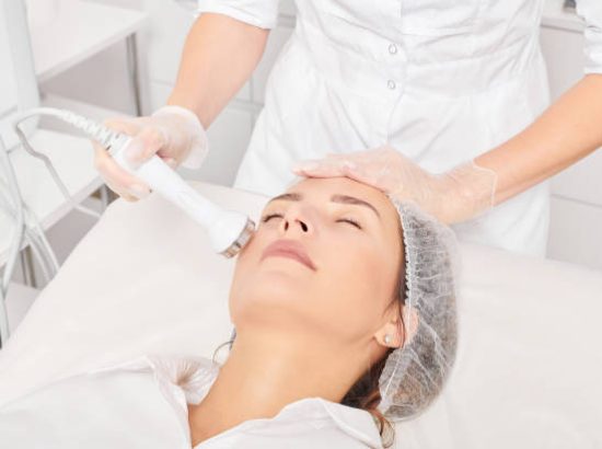 Beautician makes ultrasound skin tightening for rejuvenation woman face using phonophoresis, anti aging cosmetic procedure with in beauty spa salon. Cosmetologist makes ultrasonic skincare lifting